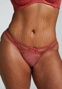Lace lingerie set in reddish-brown, featuring a sheer fabric, floral pattern, and double strap design. Accented with a small bow.