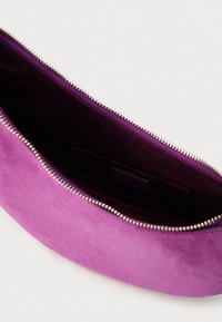 Fialová semšová kabelka do ruky so zipsovým zapínaním, ktorá má hladkú textúru a vnútornú kapsu. Detaily na zips pozdĺž hornej hrany.