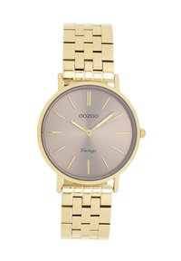 Montre en métal doré avec un cadran argent-gris en soleil, des marqueurs d'heure fins et un bracelet lisse. Elle présente un boîtier rond et un design minimaliste.