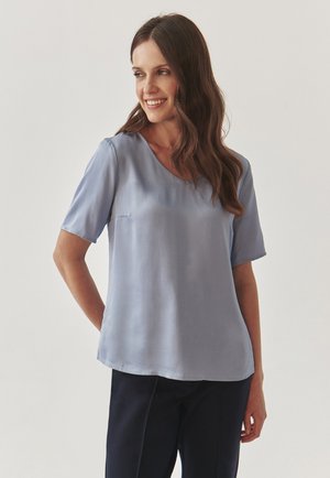 Lichtblauw zijden blouse met een V-hals en korte mouwen; gladde textuur en ontspannen pasvorm met een subtiele glans. Geschikt voor casual of formele gelegenheden.