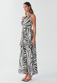 Schwarz-weißer Zebra-Print Maxi-Kleid mit einem schulterfreien Design und gerafft Taille. Der Stoff wirkt leicht und hat eine fließende Textur.