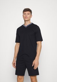 Sort T-shirt med korte ærmer og V-hals, med en krave i blå og hvid stribe. Sammen med matchende sorte shorts.