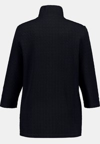 Black textured long-sleeve jacket with a high neck and straight hem, shown from the back on a plain background.
