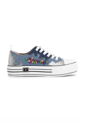 Le sneakers in denim e argento presentano una punta in gomma bianca, una suola a strisce e un motivo floreale ricamato con accenti colorati.