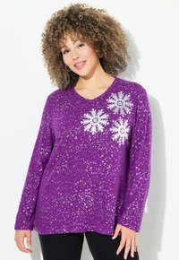 Suéter morado de manga larga con cuello en V, que presenta un patrón de copos de nieve plateados y un diseño moteado. Tejido suave y corte holgado.