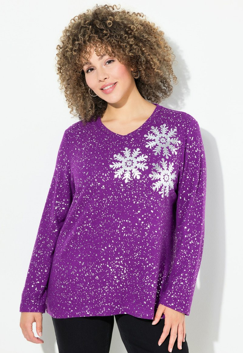Suéter morado de manga larga con cuello en V, que presenta un patrón de copos de nieve plateados y un diseño moteado. Tejido suave y corte holgado.