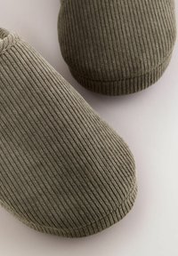 Zelene rebraste papuče s okruglim vrhom i mekanom teksturom, koje imaju nisku siluetu i bešavne rubove za minimalistički dizajn.