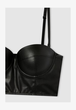 Reggiseno senza spalline in pelle nera con coppe sagomate, una superficie liscia e un design strutturato con dettagli delle cuciture. Inclusi spallacci neri regolabili.