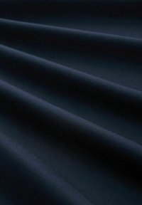 Tejido de un azul marino oscuro con una textura suave y mate, que presenta suaves pliegues caídos que muestran variaciones sutiles en el sombreado y la forma.