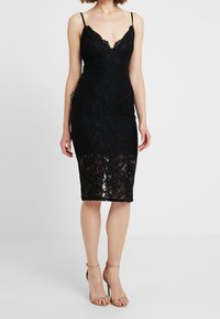Černé krajkové midi šaty s hlbokým výstřihem a tenkými ramínky; přiléhavý silueta se průhlednými krajkovými detaily na lemu. Hladký povrch látky.