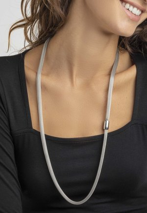 Collar de malla plateada con un cierre metálico suave, que presenta un diseño alargado y elegante que cae suavemente alrededor del cuello.