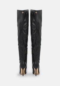 Botas negras por encima de la rodilla, hechas de cuero suave, con un diseño ajustado, tacones altos de aguja y acentos de hardware en tono dorado.