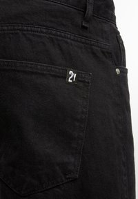 Črne denim hlače imajo stransko žep z belim oznako "2Y", dvojno šivanje in kovinski zakovico. Gladka, teksturirana površina.