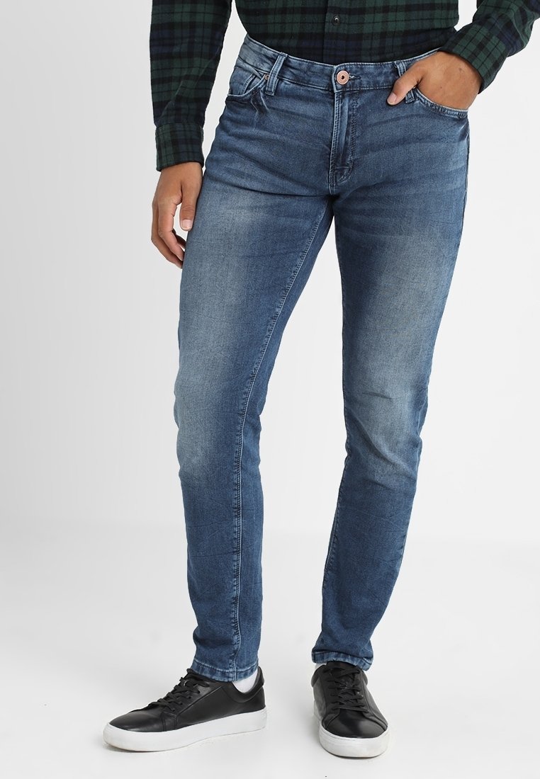 Slim-fit blå jeans med en blekt tvätt, femficksdesign och knappstängning. Kombineras med svarta sneakers för en avslappnad look.