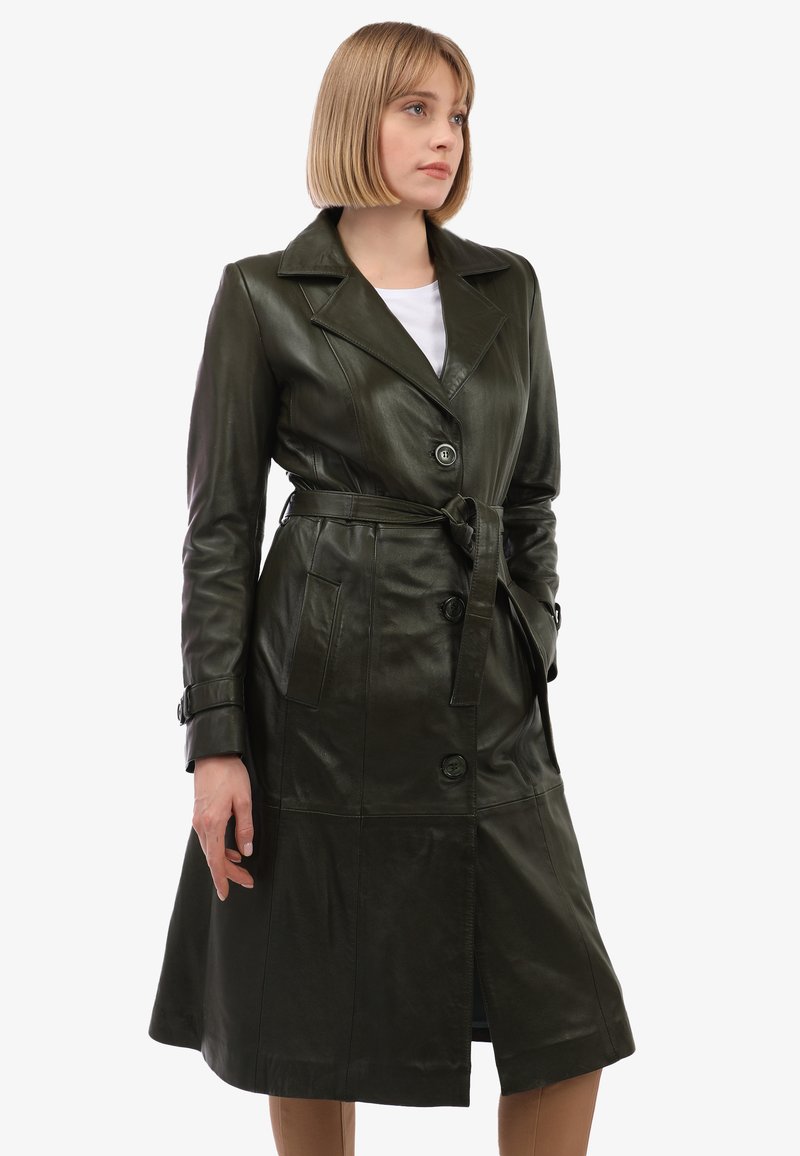 Manteau trench en cuir vert foncé avec une ceinture à nouer, boutons doubles et poches latérales. Il présente un col cranté et une conception mi-longue.