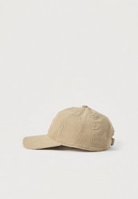 Beige kordfløyel baseballcaps med buet brem, vertikalt teksturmønster og justerbar stropp bak. Enkel design og lett tekstur.