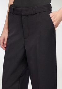 Czarne dopasowane spodnie o gładkiej teksturze, slim fit, z pętelkami na pasek, bocznymi kieszeniami oraz z przodem na zamek, co zapewnia elegancki wygląd.