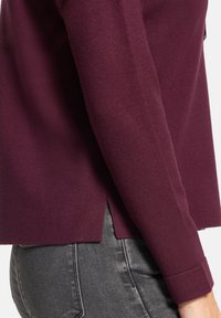 Bordowy sweter dziany o prostym kroju z bocznymi rozcięciami, z dopasowanym rękawem i gładką, miękką fakturą.