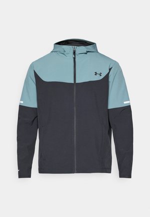 Veste à capuche avec une partie supérieure bleu clair et une partie inférieure bleu marine. Fabriquée en tissu léger avec une fermeture éclair et des poches latérales.