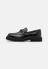 Svarte skinnloafers med rund tå, dekorativ stropp og tykk strukturert såle for godt grep. Glatt overflate med minimal dekor.