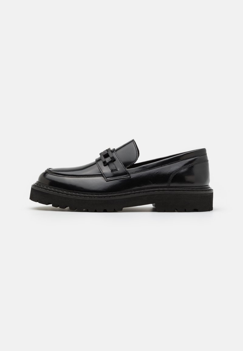 Svarte skinnloafers med rund tå, dekorativ stropp og tykk strukturert såle for godt grep. Glatt overflate med minimal dekor.