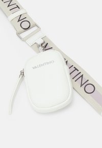 Borsa in pelle bianca con superficie texturizzata, dotata di una cerniera e di una tracolla stampata con "VALENTINO" in colori a contrasto.