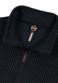 Navy sininen, vetoketjullinen fleecepusero, jossa on ribbireunus, korkea kaulus ja Colmar Originals -logo, jossa on punaisia, valkoisia ja harmaita raitoja.