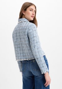 Blauwe tweedjas met een textuurweefsel, cropped ontwerp en rafelige zoom, gecombineerd met blauwe denimjeans.