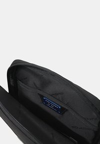 Custodia per laptop nera con chiusura a zip, caratterizzata da una texture liscia, tasche interne e un'etichetta blu con il marchio "AQUADRO".