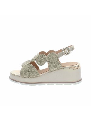 Sandale beige à talon compensé avec des brides circulaires tressées et une boucle ajustable à la cheville, avec un bout fermé et une semelle plateforme solide.