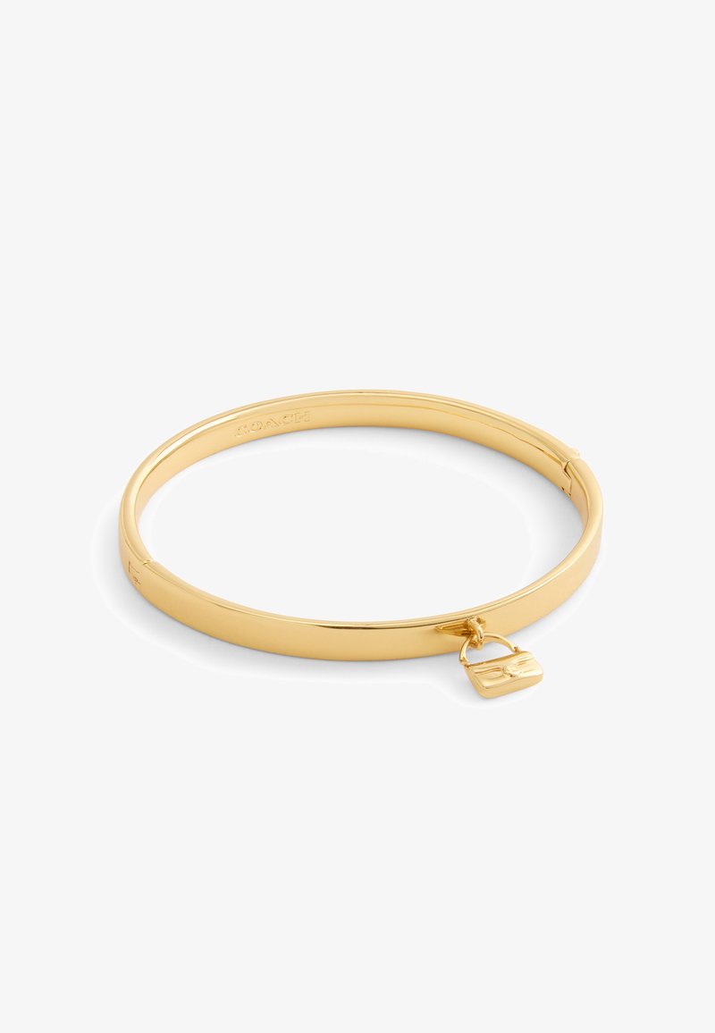 Goldfarbener Armreif mit glatten, abgerundeten Kanten, der einen kleinen Charm in Form einer Handtasche zeigt. Sauberes Design, glänzende Oberfläche.