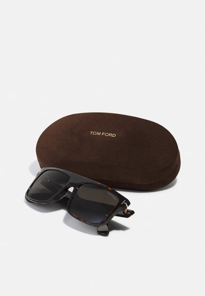 Ochelari de soare cu un cadru din fibră de broască țestoasă, lentile întunecate și accesorii din argint. Însoțiți de un toc moale maro, cu "TOM FORD" embosat în aur.