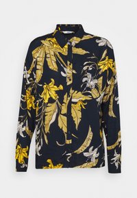Blouse bleu marine à manches longues avec imprimé floral tropical jaune et blanc, devant boutonné et col classique.