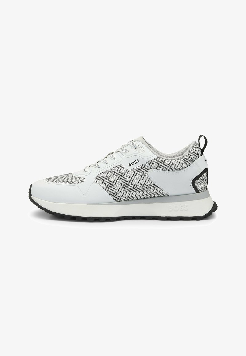 Chaussure de sport blanche et grise avec tige en maille, semelle en caoutchouc et accents noirs contrastants. Lacets et logo visibles sur le côté.