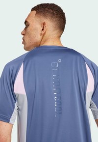 Modrá sportovní tričko s krátkým rukávem, význačné světlými šedými a růžovými akcenty, prodyšný materiál a reliéfní logo "CLIMACOOL" na zadní straně.
