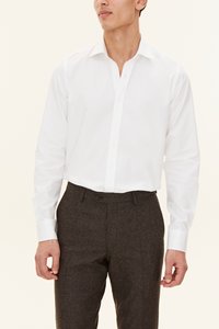 Vit långärmad skjorta med spetsig krage och knappslå fram, kombinerad med bruna texturerade byxor. Slät tyg, skarp design.