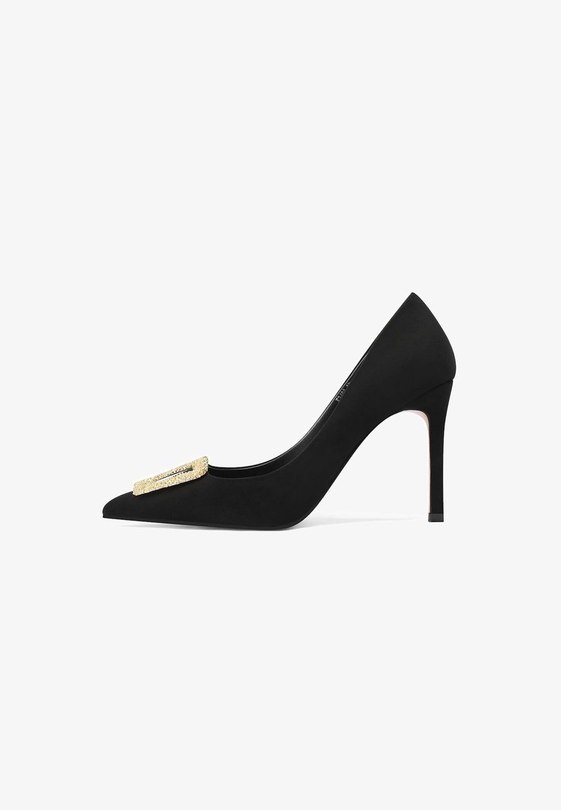 Pump nera con tacco alto realizzata in morbido suede, con punta affusolata e una fibbia decorata in tono oro sulla parte superiore per un tocco di dettaglio in più.