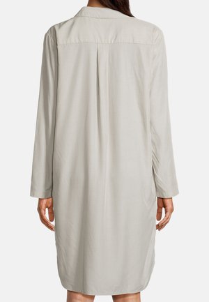 Kvinde iført en langærmet, knælængde, lysegrå skjortekjole, vist bagfra med en central rygplissé og løs pasform.