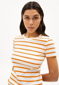 Gestreept T-shirt met korte mouwen, met afwisselend witte en oranje horizontale strepen. Gemaakt van ribbenstof en heeft een ronde halslijn.