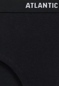 Czarna bawełniana bielizna w jednolitym wzorze, elastyczny pas materiału z białym logo "ATLANTIC" oraz gładka tekstura z minimalnymi szwami.