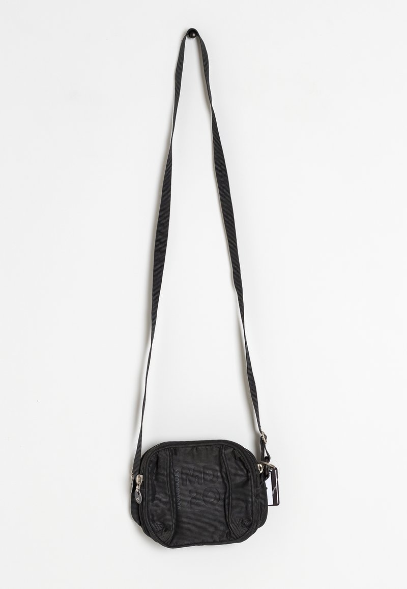 Malá černá crossbody taška s nastavitelným popruhem, zipovým uzávěrem a jemně texturovaným vzorem, visící na bílém pozadí.