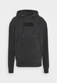 Sudadera negra con bolsillo canguro frontal, tela texturizada y parche en relieve en el pecho. Cuenta con cordones ajustables y puños acanalados.
