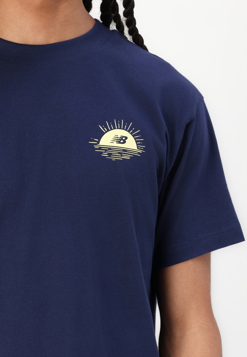 Camiseta de algodón azul marino con un gráfico de sol amarillo con rayos y agua, situado en el área del pecho izquierdo. Mangas cortas, corte estándar.