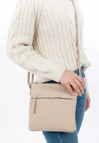 Borsa a tracolla in pelle beige con tasca frontale con zip, texture liscia, forma quadrata e tracolla regolabile.