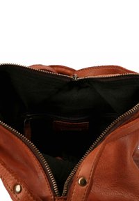 Sac à main en cuir brun avec une fermeture éclair, présentant un intérieur spacieux en tissu noir et une poche zippée intérieure pour l'organisation.