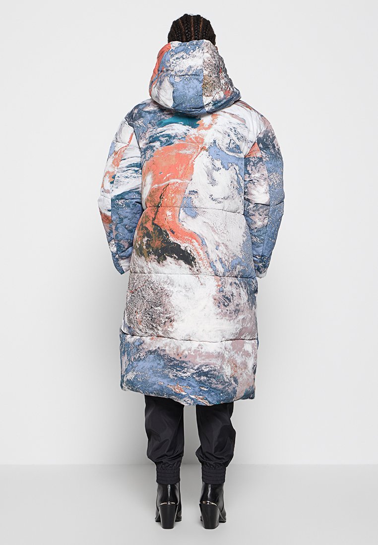 Doudoune avec un motif abstrait coloré dans des tons de bleu, d'orange et de blanc ; elle présente une capuche et un design long matelassé.