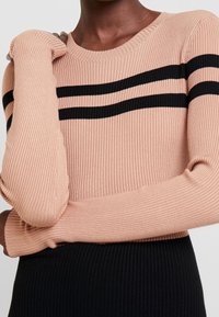 Strickpullover in sanftem Rosa mit schwarzen horizontalen Streifen. Verfügt über eine gerippte Textur, einen runden Ausschnitt und eng anliegende Ärmel.