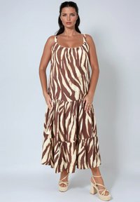 Bruin en crèmekleurige gelaagde maxi jurk met een zebraprint patroon, voorzien van dunne bandjes en een vloeiende stijl. G gedragen met strappy wedge sandalen.