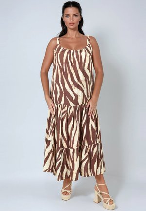 Bruin en crèmekleurige gelaagde maxi jurk met een zebraprint patroon, voorzien van dunne bandjes en een vloeiende stijl. G gedragen met strappy wedge sandalen.