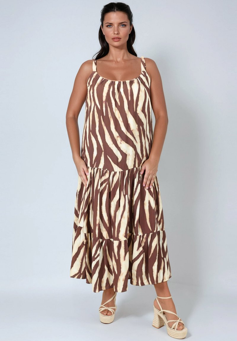 Bruin en crèmekleurige gelaagde maxi jurk met een zebraprint patroon, voorzien van dunne bandjes en een vloeiende stijl. G gedragen met strappy wedge sandalen.